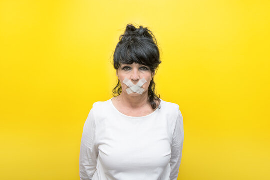 aged woman with a sealed mouth on a yellow background, the concept of censorship, prohibition