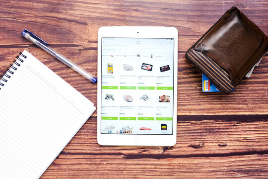 A picture of online groceries browsing page with wallet, credit card and notebook.