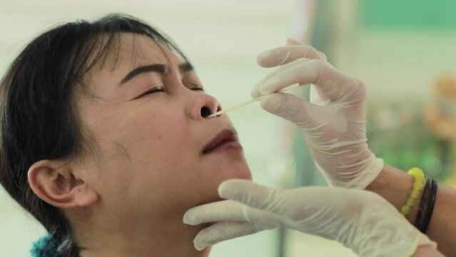 Doctor's hand uses an antigen test kit with a middle-aged woman sitting to check her mucus or secretions to test and prevent COVID-19 infection Omikron : To prevent infection and spread of COVID-19