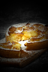 Apple tart covered in icing sugar on a wooden chopping board.  With lighting effect