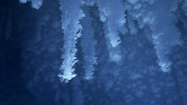 Beautiful crystal icicles, blue sharp ice snowflakes inside frozen cave 
