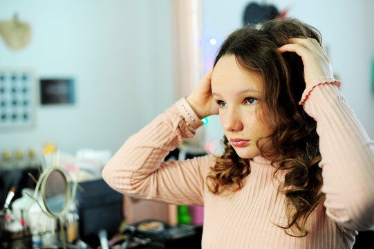 a girl in a make-up studio tinager in pink golf smiles happy with a new makeup in her eyes reflects a lamp for photography gently painted eyelashes and lips hair blonde girl 10-13 years old.