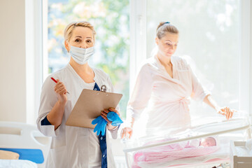 Portrait of female doctor, breastfeeding specialist, nurse making notes in medical records,...