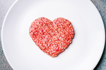 Fototapeta na wymiar Meat cutlet in the shape of a heart. Dinner for lovers on February 14th. Meat love. Valentine's Day. Mince heart