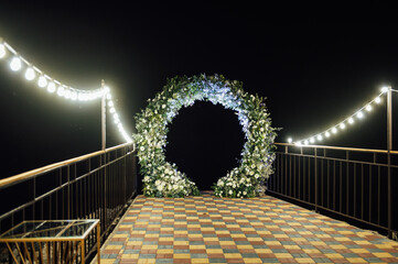 Round wedding arch decorated with fresh flowers. Evening ceremony