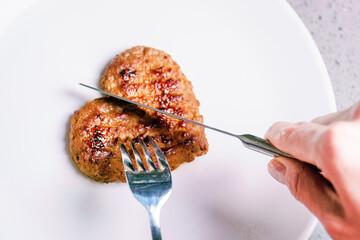 Eating minced heart on a plate. Meat love. Valentine's Day. Dinner for lovers on February 14. Meat cutlet in the shape of a heart