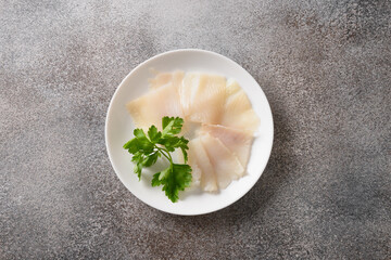 Delicious smoked halibut slices served in white plate isolated on gray background. View from above.