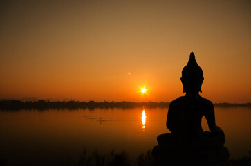 Silhouette buddha on sunset background.
