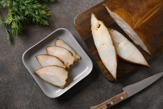 Fresh smoked halibut slices cutted on brown background. View from above.