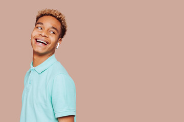 Glad young afro latin american man feels great, wears in green shirt, listens to a new exciting...