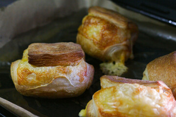 Homemade pastry puff buns with cheese on a baking sheet close-up