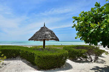 Resort with sun lounger with parasol made of palm branches on the blue indian ocean with sandy...