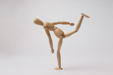 a wooden mannequin of a man swung his leg for a kick on a white background