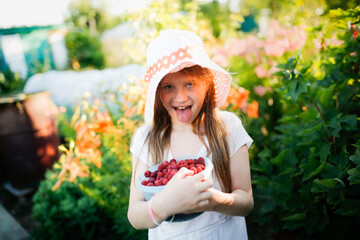 Cute European girl child teenager with big bowl of raspberries, Daughter helps pick berries in garden, eco-friendly healthy eating natural berries