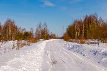 winter road through the forest to the village