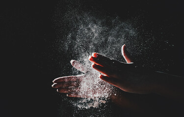 woman chef hand clap with splash of white flour and black background with copy space.