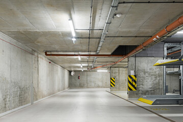 Garaż podziemny z miejscami parkingowymi. Ściany garażu wykonane z betonu. Parking na platformie. Oszczędność miejsc parkingowych - obrazy, fototapety, plakaty