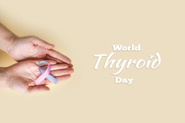 World Thyroid Day. Adult hands holding Thyroid cancer awareness ribbon in Teal Pink Blue. Problems with thyroid. Polycystic disease. World cancer day