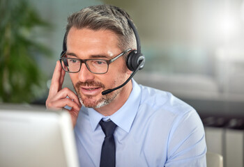 No dreams truly runs cold. Shot of a mature man using a headset and talking to clients while using...