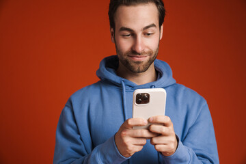 Young bristle man wearing hoodie using mobile phone