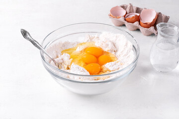 Kneading the dough for bakery product. Adding eggs into yeast dough in the glass bowl. Preparing buns, Easter cake or pie. Step by step recipe. Step 4