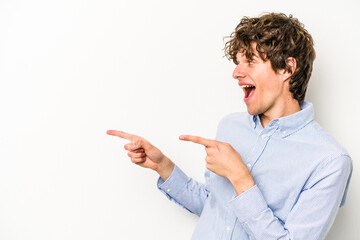 Young caucasian man isolated on white background points with thumb finger away, laughing and carefree.