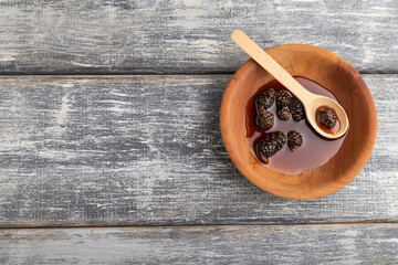 Pine cone jam in wooden bowl, top view, copy space.