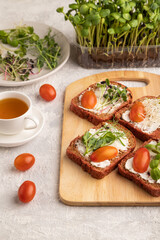 Red beet bread sandwiches with cream cheese, tomatoes and microgreen on gray. side view.
