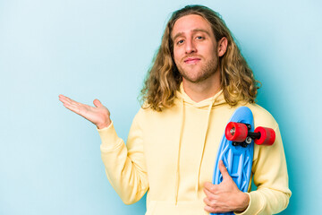 Young skater caucasian man isolated on blue background showing a copy space on a palm and holding another hand on waist. © Asier