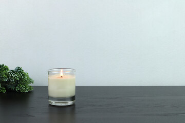 a burning luxury aromatic scented candle glass is on black wooden table and background of grey...