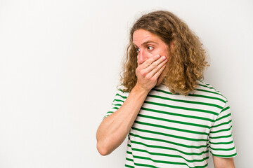 Young caucasian man isolated on white background thoughtful looking to a copy space covering mouth with hand.