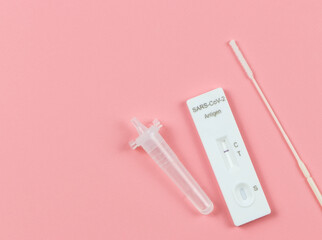 Covid-19 negative test result antigen test kit (ATK)  with a nasal swab on pink background with copy space. Antigen test kit for self collect nose swab.