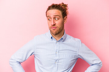 Young caucasian man isolated on pink background confused, feels doubtful and unsure.