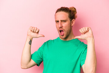 Young caucasian man isolated on pink background feels proud and self confident, example to follow.