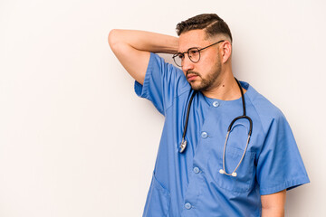 Hispanic nurse man isolated on white background touching back of head, thinking and making a choice.