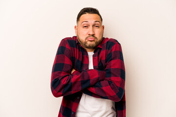 Young hispanic man isolated on white background shrugs shoulders and open eyes confused.