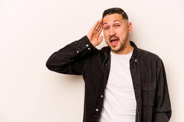 Young hispanic man isolated on white background shouts loud, keeps eyes opened and hands tense.