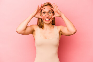 Young caucasian woman isolated on pink background keeping eyes opened to find a success opportunity.