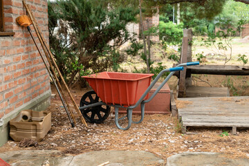 Red wheelbarrow in the yard with trees in the background