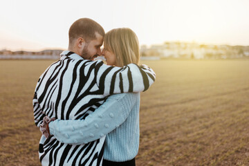 Happy couple looking each other and touching noses in countryside at sunset. Girlfriend and boyfriend.