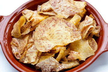 Crispy taro chips in bowl on white background.