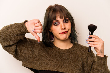 Young caucasian makeup artist woman holding a makeup brush isolated on white background showing a...