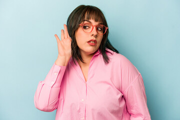 Young caucasian woman isolated on blue background trying to listening a gossip.