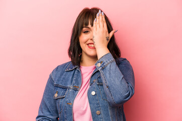 Young caucasian woman isolated on pink background having fun covering half of face with palm.