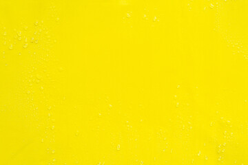 Yellow smooth surface with drops of water as textural background