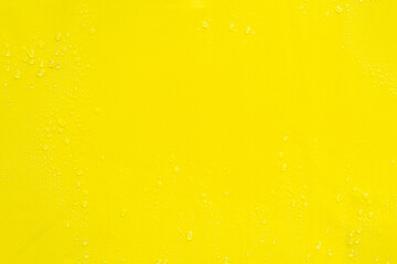 Yellow smooth surface with drops of water as textural background