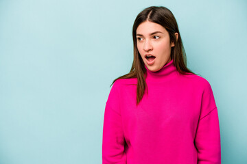 Young caucasian woman isolated on blue background being shocked because of something she has seen.