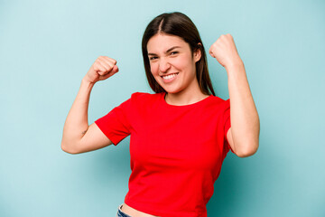 Young caucasian woman isolated on blue background cheering carefree and excited. Victory concept.