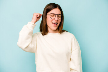 Young caucasian woman isolated on blue background celebrating a victory, passion and enthusiasm, happy expression.