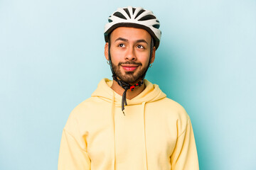 Young hispanic man wearing helmet isolated on blue background dreaming of achieving goals and purposes